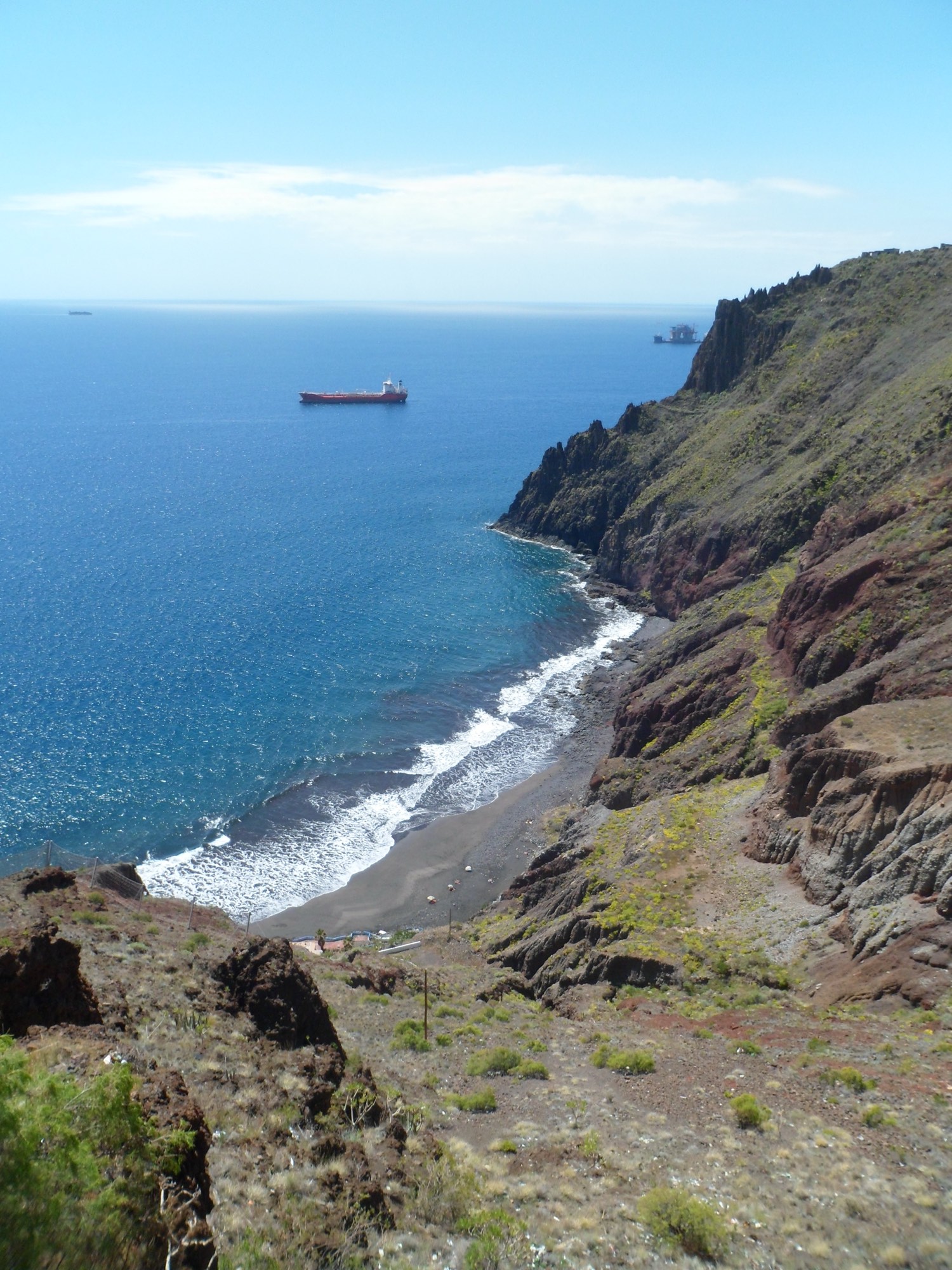 Playa de las Gaviotas — dark volcanic sand in a cove below red-ochre cliffs, deep blue Atlantic beyond